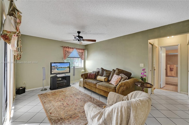 living room with ceiling fan, light tile patterned flooring, and a textured ceiling