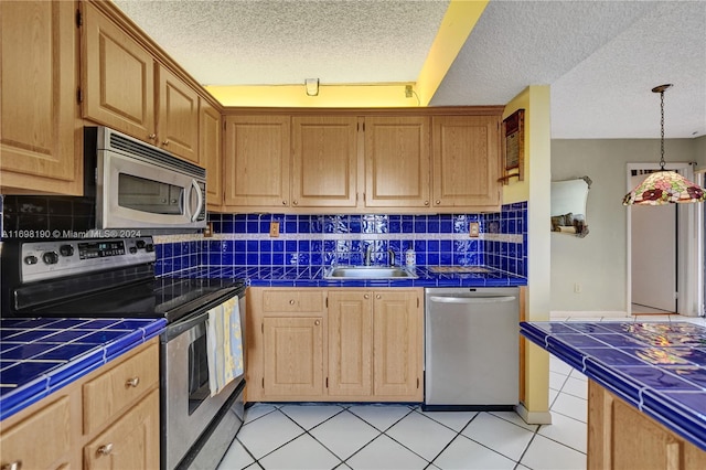 kitchen featuring tasteful backsplash, a textured ceiling, tile countertops, and stainless steel appliances