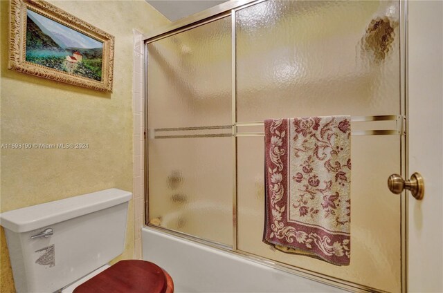 bathroom with shower / bath combination with glass door and toilet