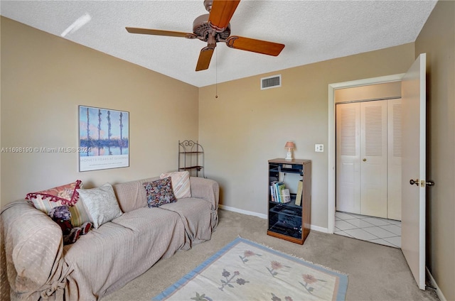 carpeted living room with ceiling fan and a textured ceiling