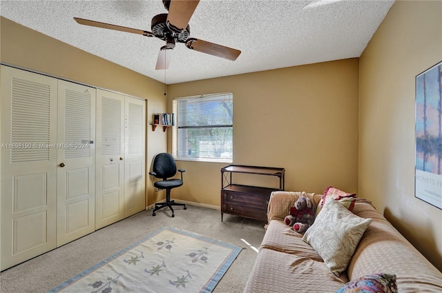 sitting room featuring a textured ceiling, light colored carpet, and ceiling fan