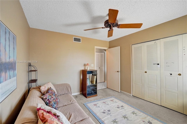 living room with ceiling fan, light colored carpet, and a textured ceiling