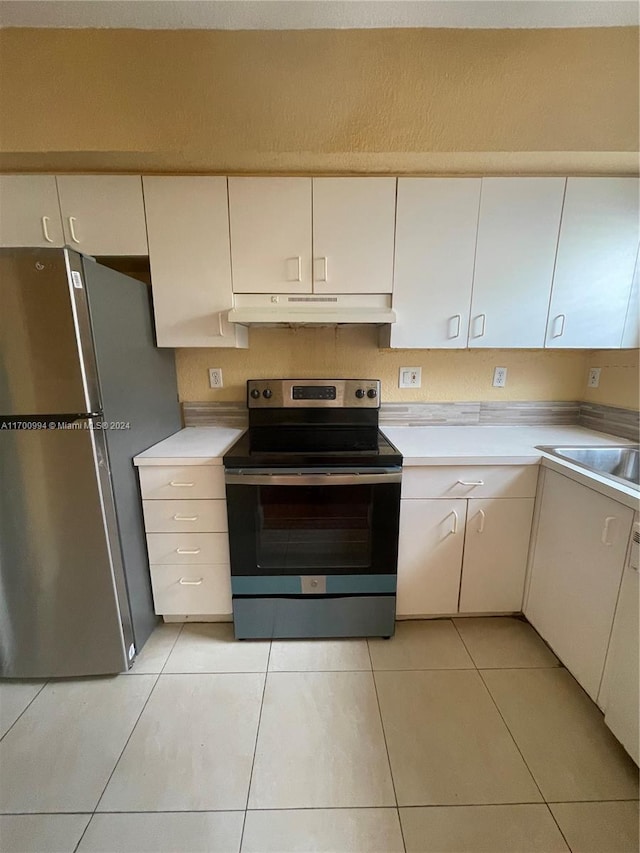 kitchen with appliances with stainless steel finishes, light tile patterned floors, white cabinetry, and sink