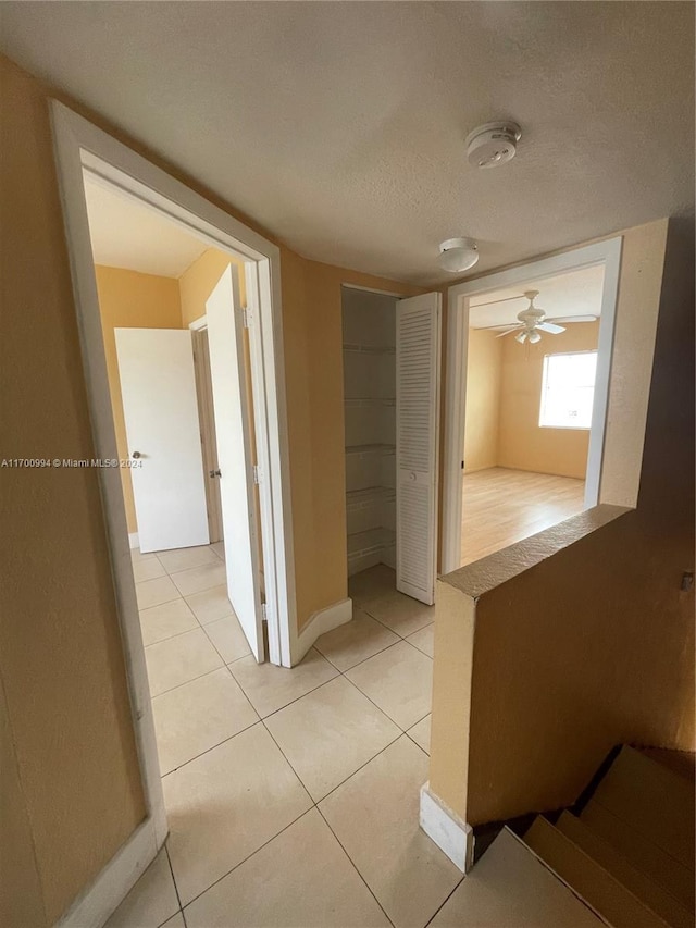 corridor with light tile patterned floors and a textured ceiling