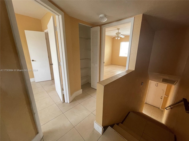 corridor featuring light tile patterned floors and a textured ceiling