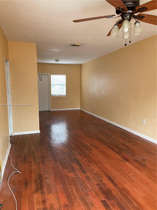 empty room with ceiling fan and dark wood-type flooring