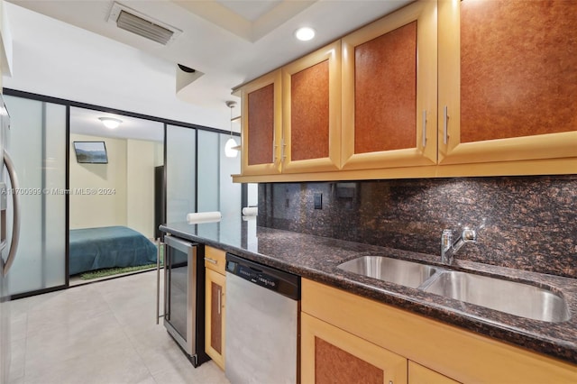 kitchen featuring decorative backsplash, stainless steel dishwasher, dark stone counters, and sink