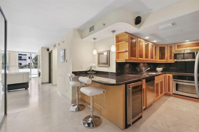 kitchen featuring kitchen peninsula, pendant lighting, beverage cooler, and appliances with stainless steel finishes