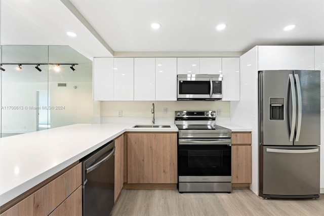 kitchen featuring sink, light wood-type flooring, white cabinetry, kitchen peninsula, and stainless steel appliances