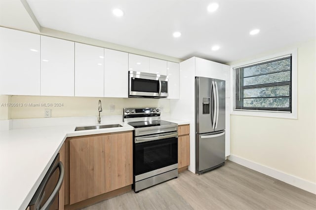 kitchen featuring light hardwood / wood-style flooring, stainless steel appliances, white cabinetry, and sink