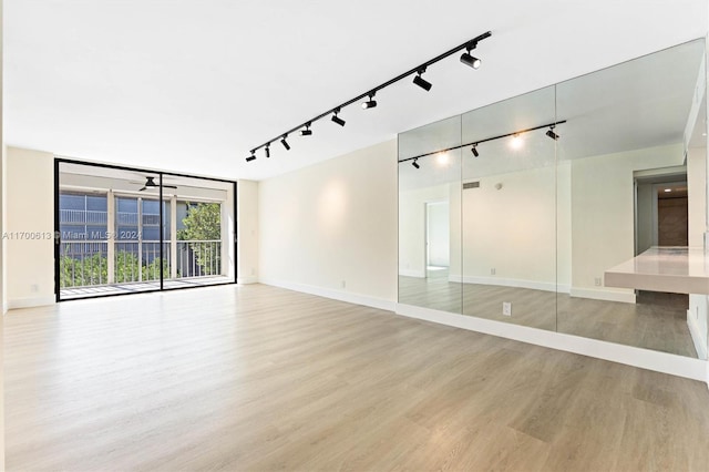 empty room with ceiling fan, track lighting, and light wood-type flooring