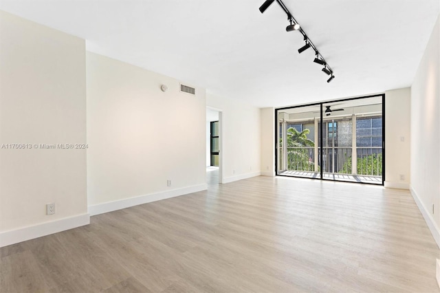 empty room featuring ceiling fan, light hardwood / wood-style flooring, and track lighting