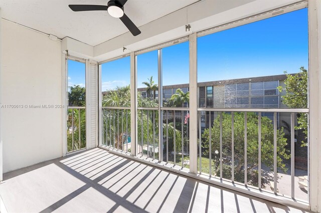 unfurnished sunroom featuring ceiling fan and a healthy amount of sunlight