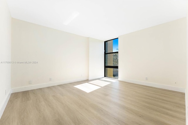 unfurnished room with expansive windows and light hardwood / wood-style flooring