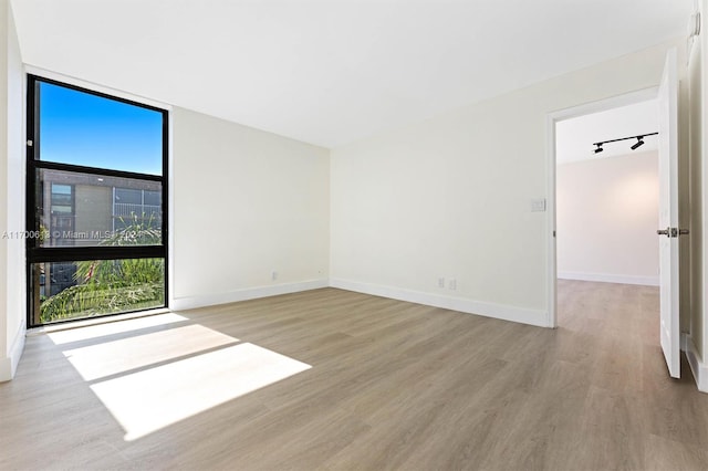 spare room with rail lighting and light hardwood / wood-style flooring