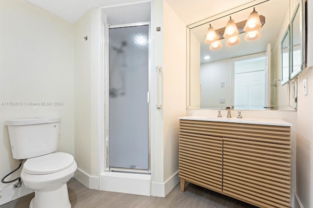 bathroom featuring hardwood / wood-style floors, vanity, a shower with shower door, and toilet