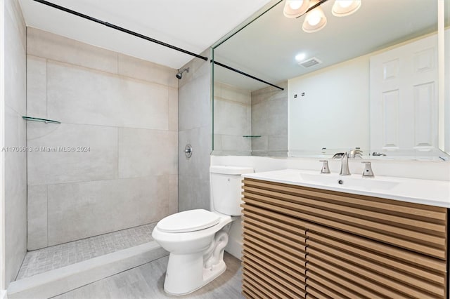 bathroom with tiled shower, hardwood / wood-style flooring, vanity, and toilet