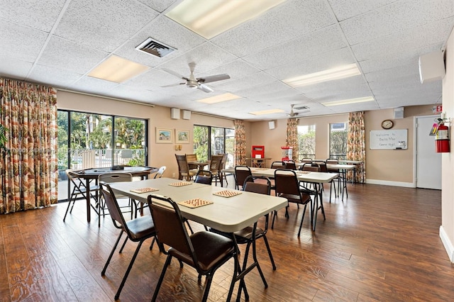 dining room with a drop ceiling, dark hardwood / wood-style floors, and ceiling fan