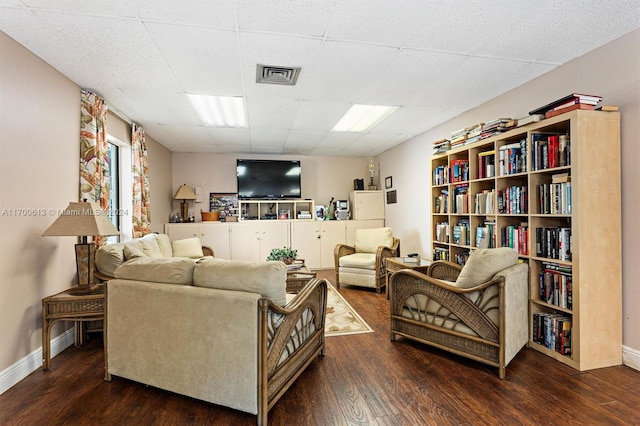 living room featuring a paneled ceiling and dark wood-type flooring