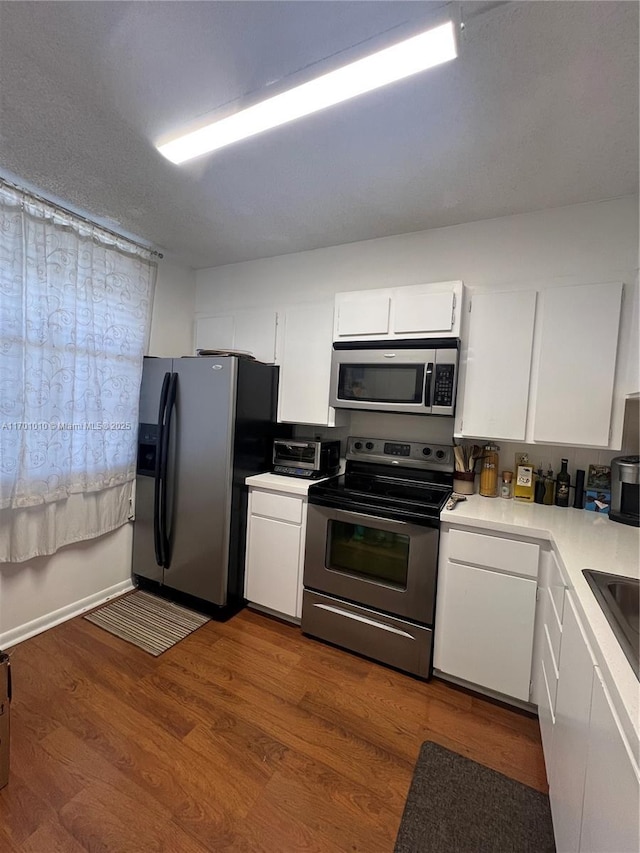 kitchen with white cabinets, appliances with stainless steel finishes, a textured ceiling, and dark hardwood / wood-style floors