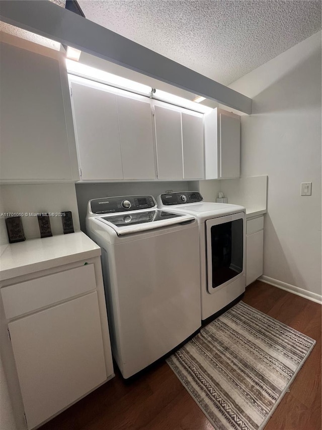 clothes washing area featuring washer and clothes dryer, cabinets, dark wood-type flooring, and a textured ceiling