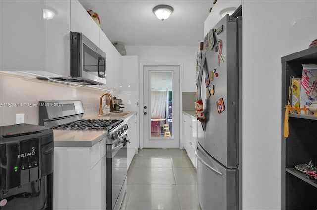 kitchen with sink, white cabinets, light tile patterned floors, and appliances with stainless steel finishes