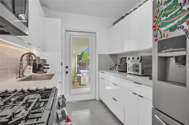 kitchen featuring white cabinetry, sink, light tile patterned floors, and stainless steel refrigerator with ice dispenser