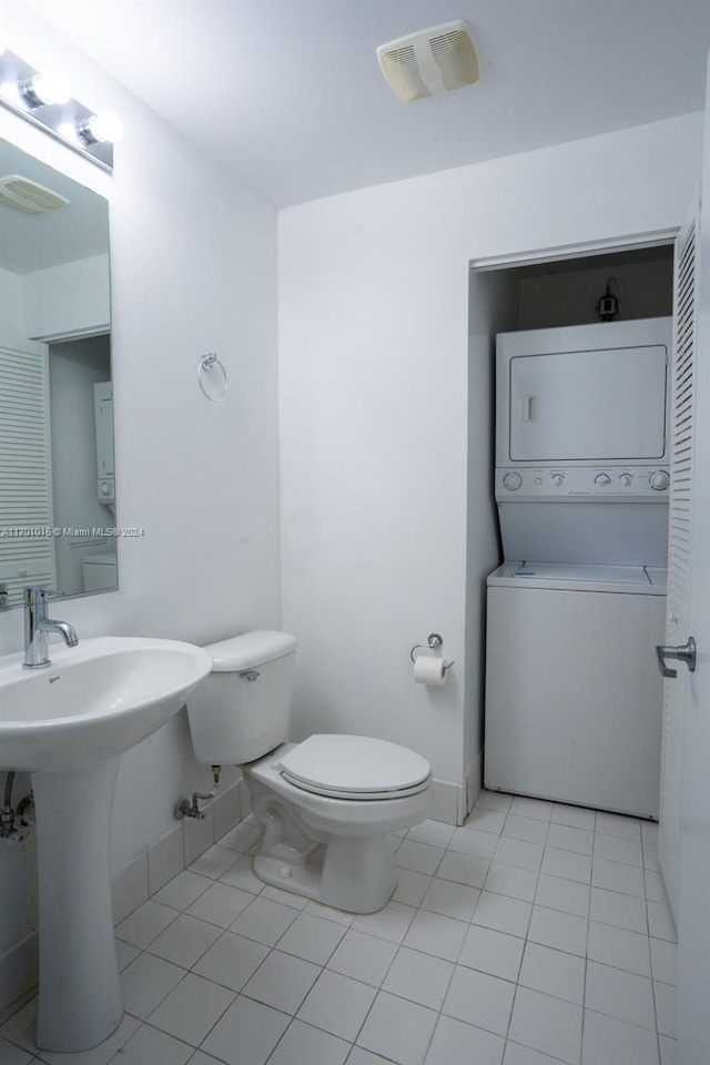 bathroom with tile patterned flooring, toilet, sink, and stacked washer and clothes dryer