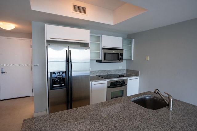 kitchen featuring dark stone counters, sink, light tile patterned flooring, white cabinetry, and stainless steel appliances