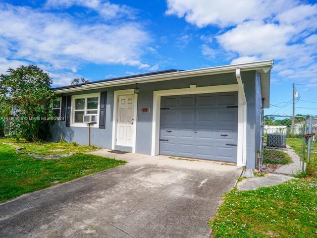 single story home with a garage, a front lawn, and cooling unit