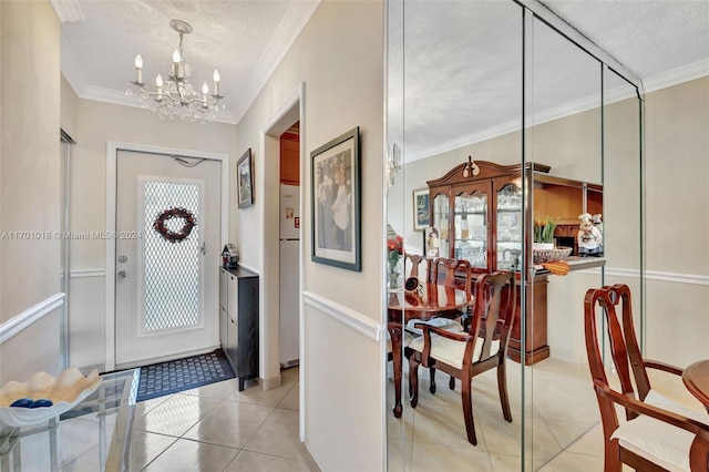 tiled foyer featuring a chandelier, a textured ceiling, and ornamental molding