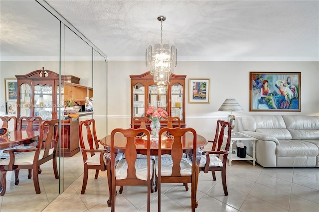 dining area featuring a notable chandelier, ornamental molding, a textured ceiling, and light tile patterned floors