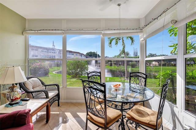 sunroom / solarium with ceiling fan and a water view