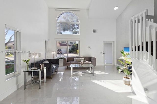 living room featuring a towering ceiling and a healthy amount of sunlight