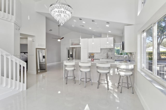 kitchen featuring a kitchen bar, sink, stainless steel fridge with ice dispenser, and white cabinets