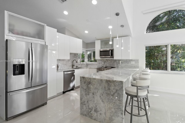 kitchen with pendant lighting, sink, appliances with stainless steel finishes, tasteful backsplash, and white cabinets