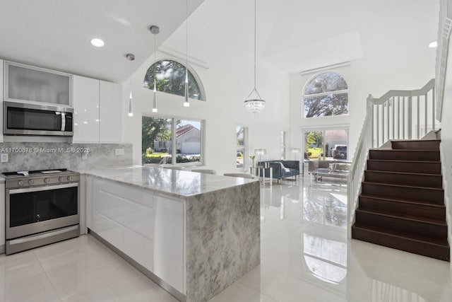 kitchen featuring pendant lighting, appliances with stainless steel finishes, plenty of natural light, white cabinets, and kitchen peninsula