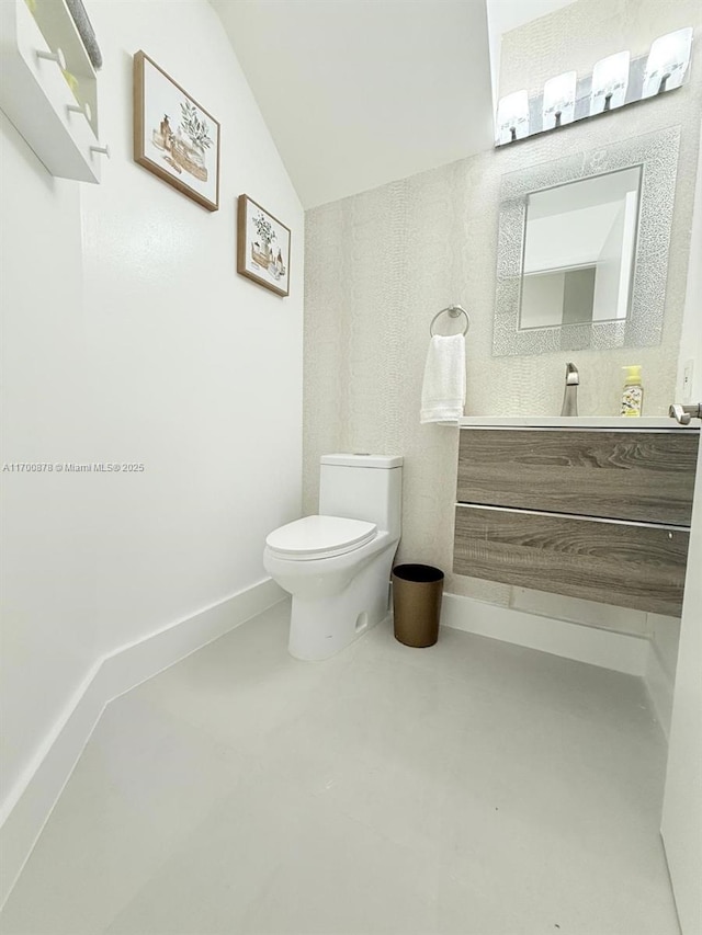 bathroom with vanity, toilet, and vaulted ceiling