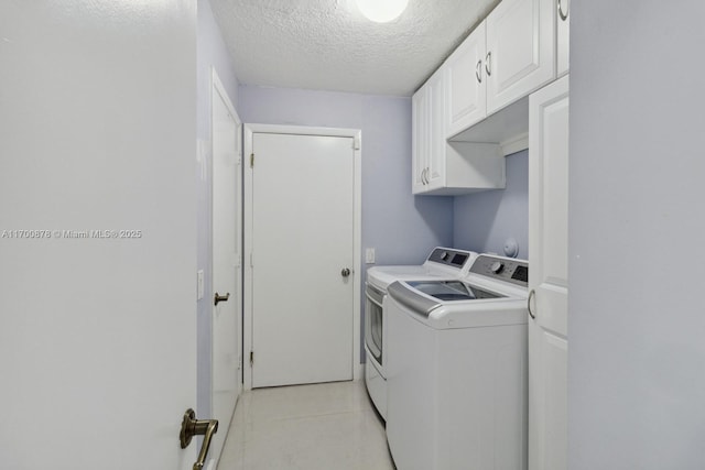 washroom featuring cabinets, light tile patterned floors, a textured ceiling, and washer and clothes dryer