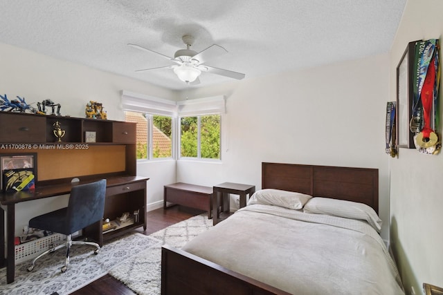 bedroom with ceiling fan, wood-type flooring, and a textured ceiling