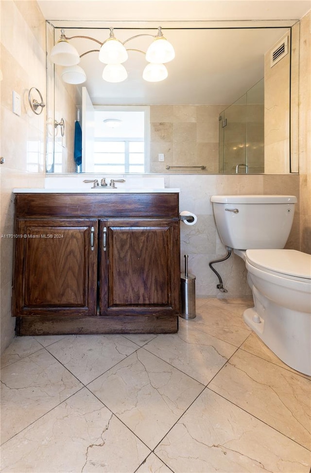 bathroom with vanity, a shower with door, toilet, and tile walls