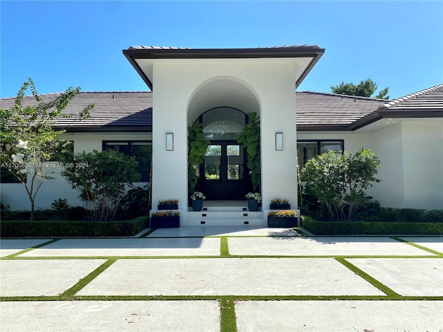 doorway to property with french doors, a tiled roof, and stucco siding