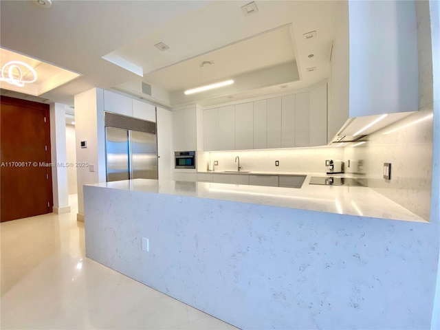 100 S Pointe Dr Unit 1207, Miami Beach, FL 33139 - kitchen featuring appliances with stainless steel finishes, a sink, white cabinetry, a peninsula, and a raised ceiling
