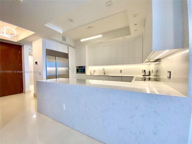 100 S Pointe Dr Unit 1207, Miami Beach, FL 33139 - kitchen with appliances with stainless steel finishes, white cabinetry, a peninsula, and a raised ceiling