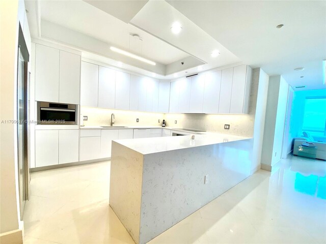 100 S Pointe Dr Unit 1207, Miami Beach, FL 33139 - kitchen featuring modern cabinets, stainless steel oven, white cabinetry, light countertops, and a peninsula