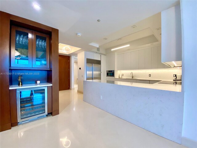 100 S Pointe Dr Unit 1207, Miami Beach, FL 33139 - kitchen with stainless steel appliances, glass insert cabinets, beverage cooler, light countertops, and white cabinetry