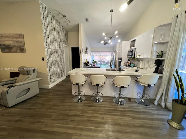 kitchen with kitchen peninsula, appliances with stainless steel finishes, dark wood-type flooring, pendant lighting, and white cabinetry