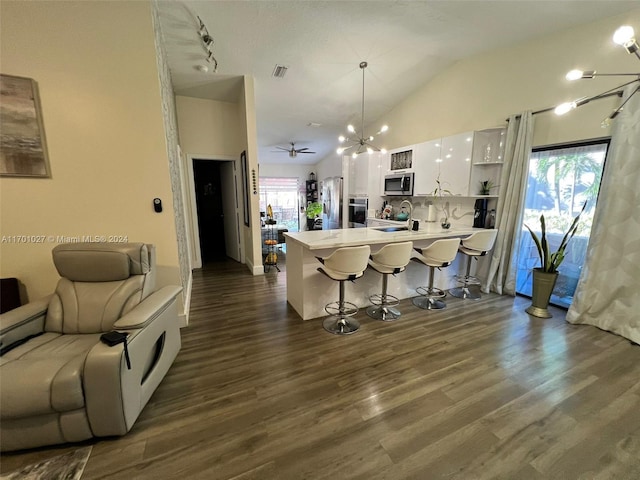 kitchen featuring a breakfast bar, dark wood-type flooring, white cabinets, hanging light fixtures, and stainless steel appliances