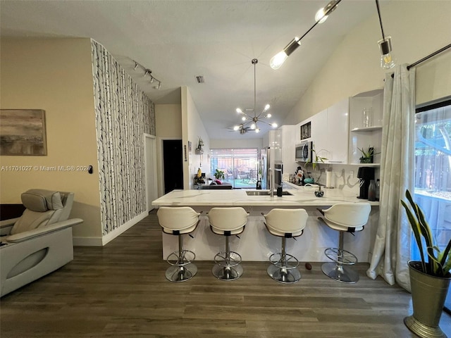 kitchen featuring a breakfast bar, decorative light fixtures, white cabinetry, and dark hardwood / wood-style floors