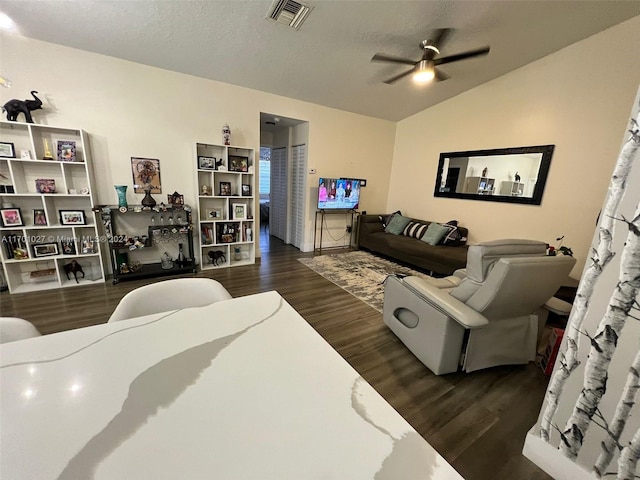 living room featuring a textured ceiling, ceiling fan, dark wood-type flooring, and lofted ceiling